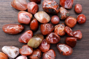 Güney Oniks, kahverengi ahşap arka planda mücevher taşlarını üst üste yığar.