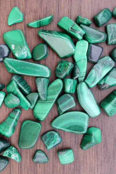 Malachite heap up jewel stones texture on brown varnished wood background
