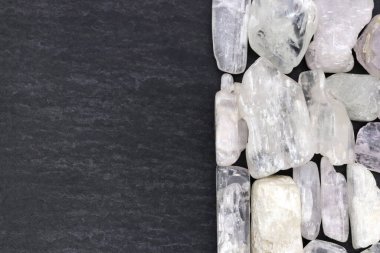 Temiz kunzite yığını mücevher taşları dokusu yarım siyah taş arka planda. Metin için yer.
