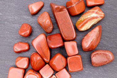 Red jasper heap up jewel stones texture on brown varnished wood background