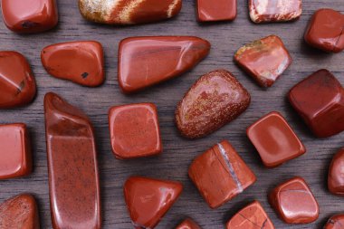 Red jasper rare jewel stones texture on brown varnished wood background