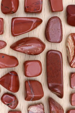 Red jasper rare jewel stones texture on light varnished wood background