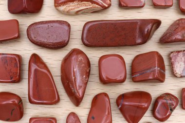 Red jasper rare jewel stones texture on light varnished wood background