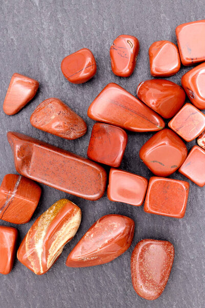 Red jasper heap up jewel stones texture on brown varnished wood background