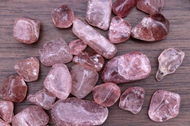 Strawberry quartz heap up jewel stones texture on brown varnished wood background