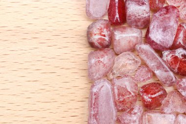 Strawberry quartz heap jewel stones texture on half light varnished wood background. Place for text.