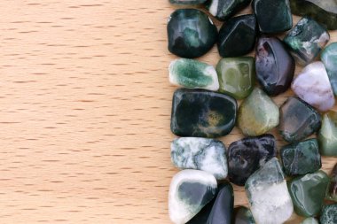 Moss agate yığın mücevher taş dokusu yarım parlak ahşap arka plan. Metin için yer.