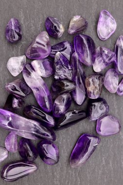 Ametist, siyah taş zemin üzerine mücevher taşları yığar.