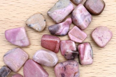 Rhodochrosite heap up jewel stones texture on light varnished wood background clipart