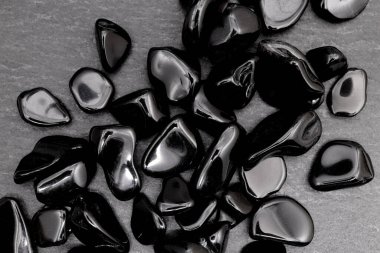 Obsidian siyah taş arka planda mücevher deseni yığıyor.