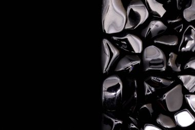 Obsidian hurda mücevher taş dokusu yarı siyah arka planda. Metin için yer.