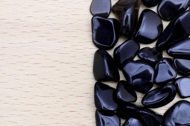 Obsidian hurda mücevher taş dokusu yarım açık renkli ahşap arka planda. Metin için yer.