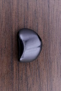 Kahverengi ahşap arka planda Obsidian mücevher taş dokusu. Makro yakın çekim.