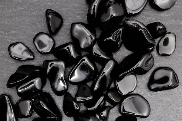Obsidian siyah taş arka planda mücevher deseni yığıyor.