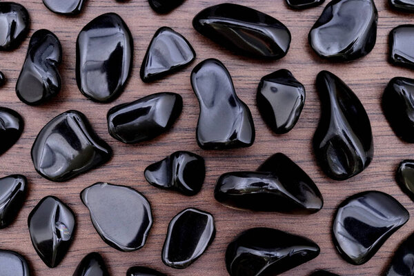 Obsidian rare jewel stones texture on brown varnished wood background
