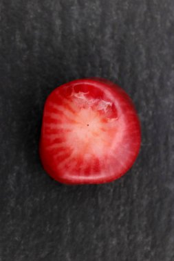 Siyah taş zemin üzerinde kırmızı mercan mücevher taşı dokusu. Makro yakın çekim.