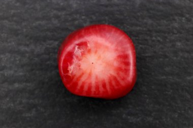 Siyah taş zemin üzerinde kırmızı mercan mücevher taşı dokusu. Makro yakın çekim.