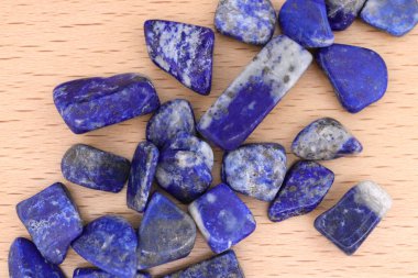 Lapis Lazuli, parlak ahşap arka plandaki mücevher taşlarını üst üste yığar.
