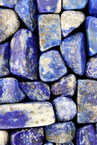 Lapis lazuli heap jewel stones texture on black background
