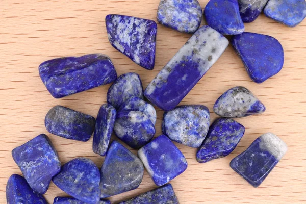 Lapis Lazuli, parlak ahşap arka plandaki mücevher taşlarını üst üste yığar.