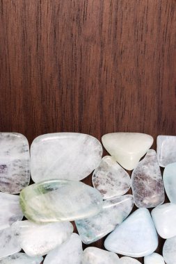 Aquamarine heap jewel stones texture on half brown varnished wood background. Place for text.