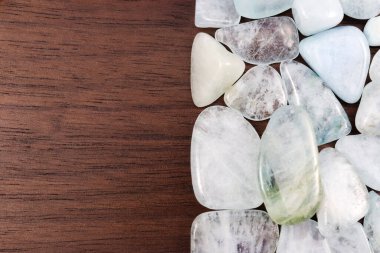 Aquamarine heap jewel stones texture on half brown varnished wood background. Place for text.