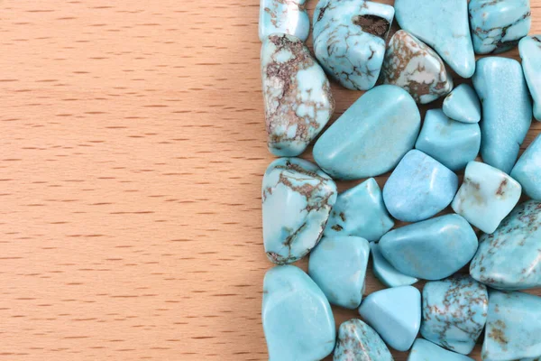 Turquoise heap jewel stones texture on half brown varnished wood background. Place for text.