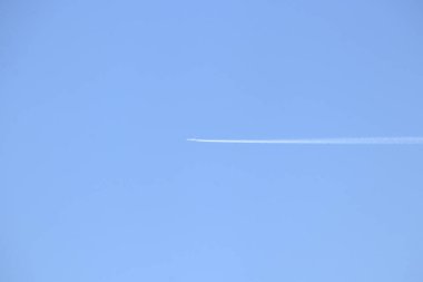 Uçak açık havada uçuyor, uzun bir kuyrukta iz bırakıyor..