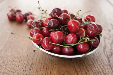 Kirazlar ahşap masada, su damlaları makro arka planda.