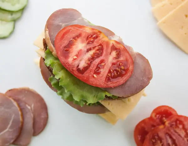 Sándwich grande con tocino y queso y verduras frescas sobre un fondo blanco — Foto de Stock