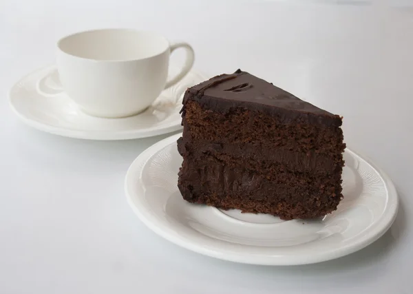 Pastel de chocolate sobre un fondo blanco con taza q — Foto de Stock