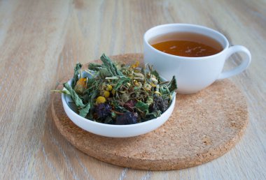 Çay yararlı otlar ve çiçek. Parlak çiçekler ve bitkiler beyaz tabak içinde kurumuş. Beyaz bir bardak bitki çayı