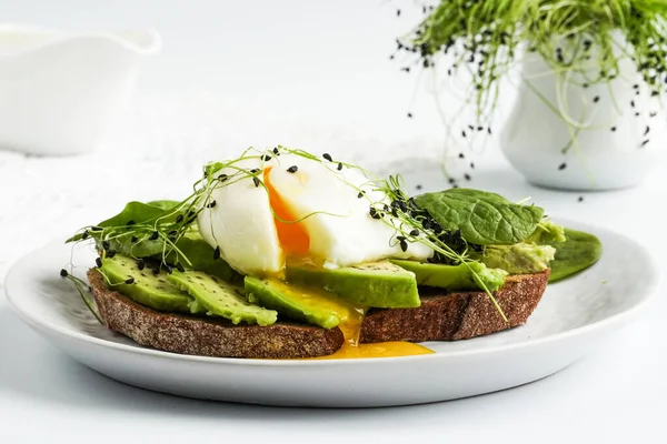 Poached egg and avocado on toast with microgreens