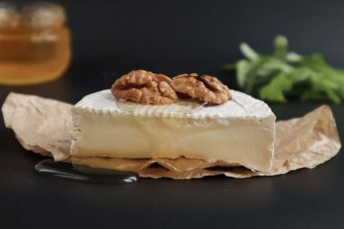 Camembert peyniri. Cevizli. Ağda kağıdında ve siyah arka planda.