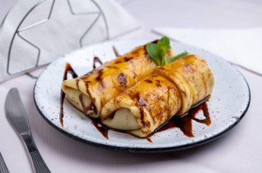 Tatlı tatlı: ev yapımı yumurta ve sütlü krep, karamel, dulce de leche, krema, çikolata ve nane yapraklı porselen tabakta..