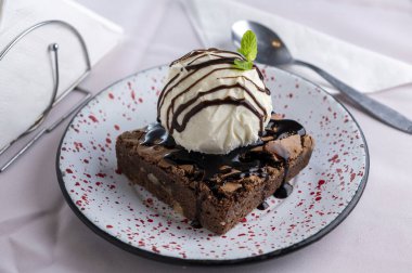 Tatlı tatlı: üstünde dondurma olan ev yapımı brownie, karamelli yumurta ve süt, dulce de leche ve krema, çikolata ve nane yaprağı porselen tabakta. 