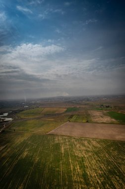 Büyük yeşil çimenleri ve bulutlu gökyüzü olan bir tarla manzarası