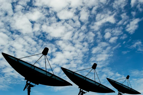 Três dados de transmissão de antenas parabólicas no fundo céu azul — Fotografia de Stock