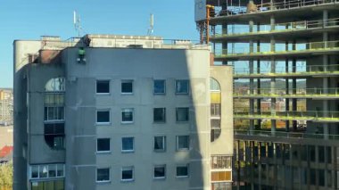 Çatıdan inen inşaat işçileri eski bir şehir binasının ön cephesini onarmak ve onarmak için emniyet kemerleri ve ipleri kullanıyorlar. Kentsel yenileme ve bakım süreci güneşli bir günde kaydedildi. Yüksek kalite 4K görüntü.
