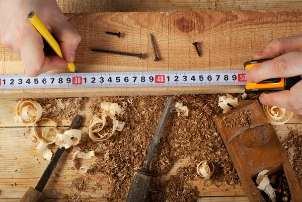 Carpintero trabajando, martillo, medidor y destornillador sobre fondo de construcción — Foto de Stock