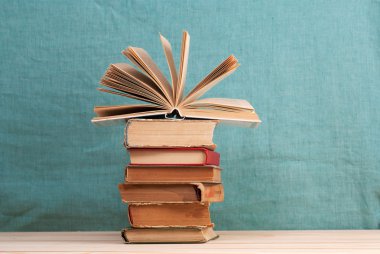 Açık kitap, ahşap masa üzerinde ciltli kitap yığını. Okula dönüş. Kopya alanı