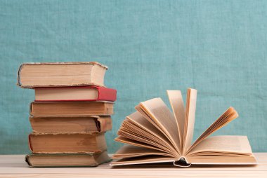 Açık kitap, ahşap masa üzerinde ciltli kitap yığını. Okula dönüş. Kopya alanı
