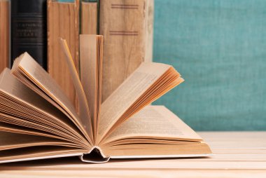 Açık kitap, ahşap masa üzerinde ciltli kitap yığını. Okula dönüş. Kopya alanı