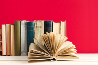Açık kitap, ahşap masa üzerinde ciltli kitap yığını. Okula dönüş. Kopya alanı
