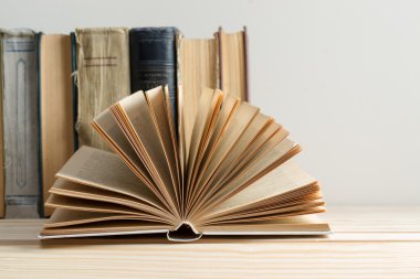 Açık kitap, ahşap masa üzerinde ciltli kitap yığını. Okula dönüş. Kopya alanı