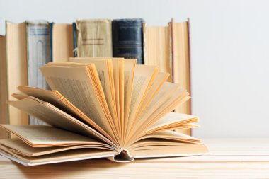 Açık kitap, ahşap masa üzerinde ciltli kitap yığını. Okula dönüş. Kopya alanı