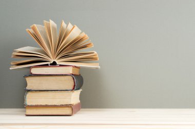 Açık kitap, ahşap masa üzerinde ciltli kitap yığını. Scho için