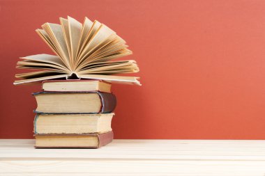 Açık kitap, ahşap masa üzerinde ciltli kitap yığını. Okula dönüş. Kopya alanı