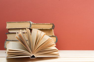 Açık kitap, ahşap masa üzerinde ciltli kitap yığını. Okula dönüş. Kopya alanı