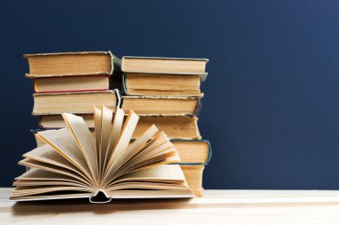 Açık kitap, ahşap masa üzerinde ciltli kitap yığını. Okula dönüş. Kopya alanı